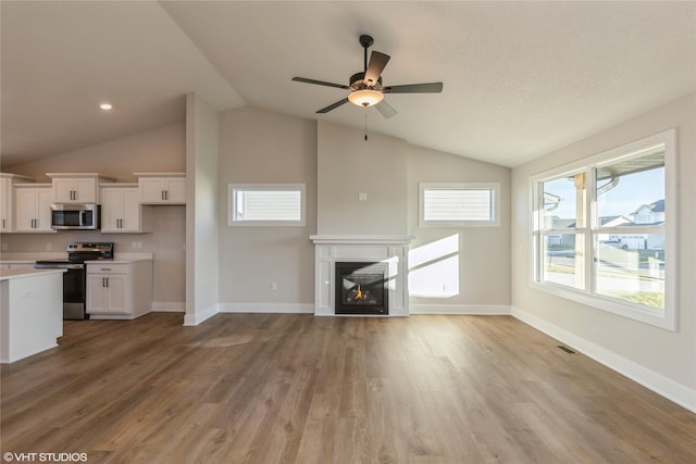 unfurnished living room featuring ceiling fan, light hardwood / wood-style flooring, and vaulted ceiling