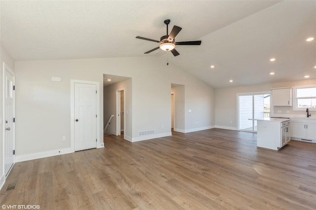 unfurnished living room featuring ceiling fan, sink, light hardwood / wood-style floors, and lofted ceiling