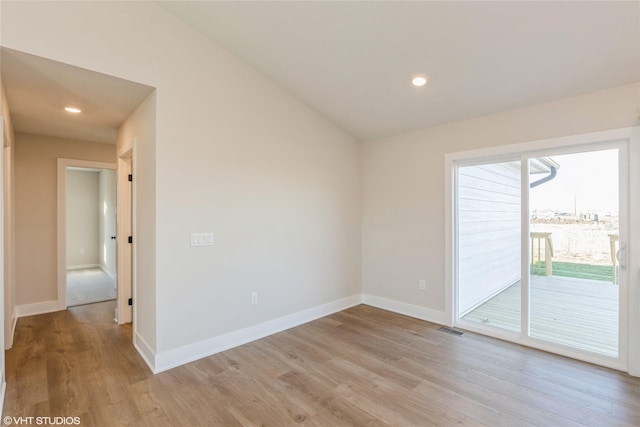 empty room with light hardwood / wood-style floors and vaulted ceiling