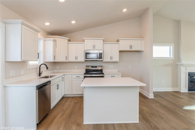 kitchen featuring white cabinetry, sink, lofted ceiling, a kitchen island, and appliances with stainless steel finishes