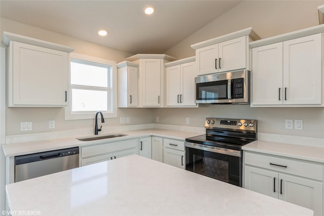 kitchen with white cabinets, sink, appliances with stainless steel finishes, and vaulted ceiling