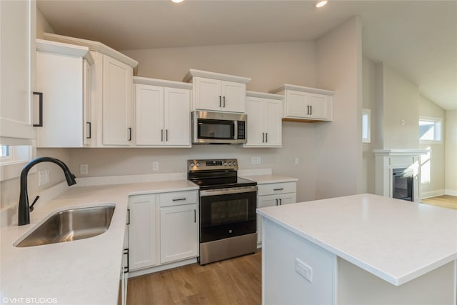 kitchen with white cabinets, sink, lofted ceiling, and stainless steel appliances