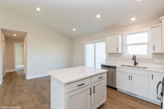 kitchen featuring stainless steel dishwasher, sink, light hardwood / wood-style flooring, white cabinets, and a kitchen island