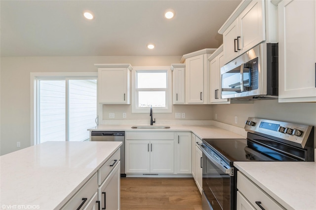 kitchen with white cabinets, stainless steel appliances, light hardwood / wood-style flooring, and sink