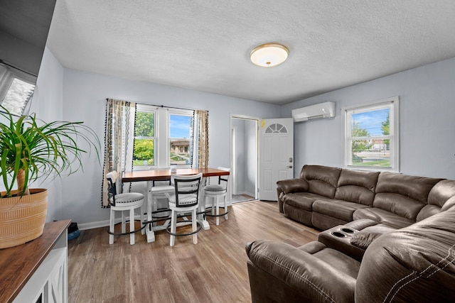 living room featuring light wood-type flooring, a wealth of natural light, and a wall mounted air conditioner