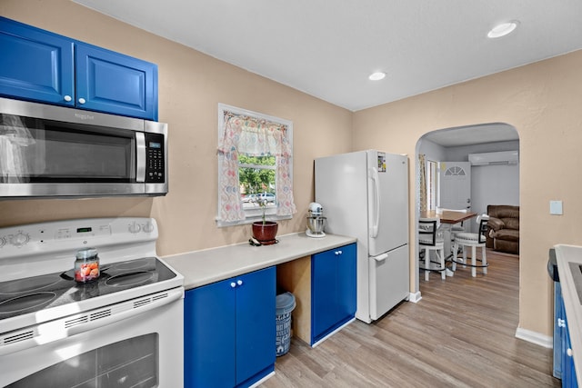 kitchen featuring white appliances, blue cabinets, a wall mounted air conditioner, and light hardwood / wood-style flooring