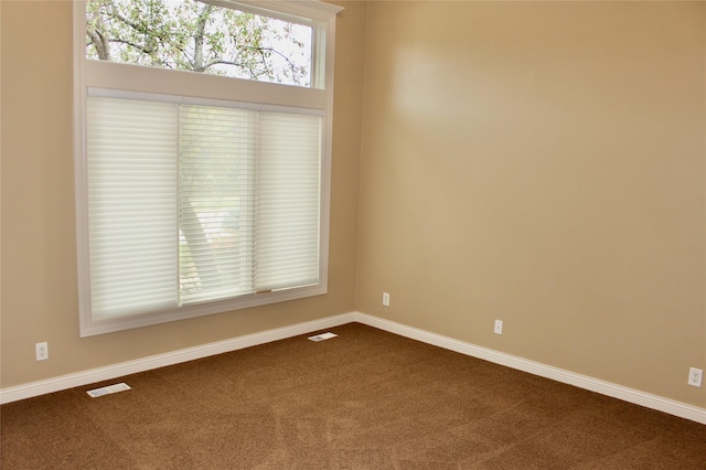 unfurnished room featuring baseboards, visible vents, and dark colored carpet