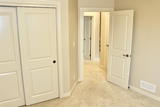 hallway featuring baseboards, visible vents, and light colored carpet