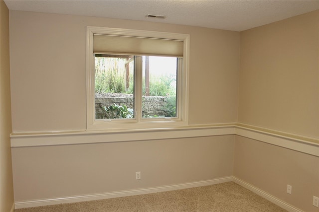 empty room featuring a textured ceiling, carpet floors, visible vents, and baseboards