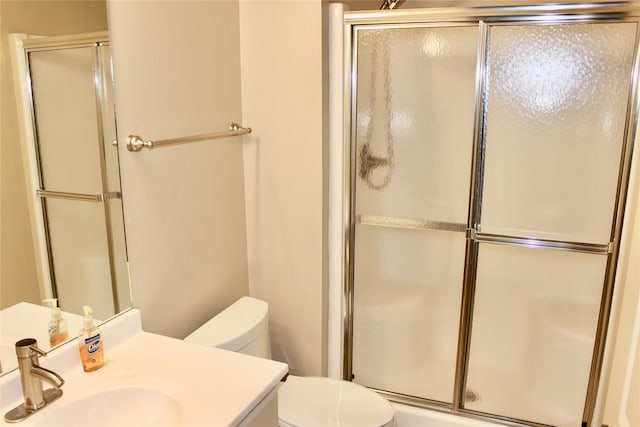 bathroom featuring a shower with door, vanity, and toilet