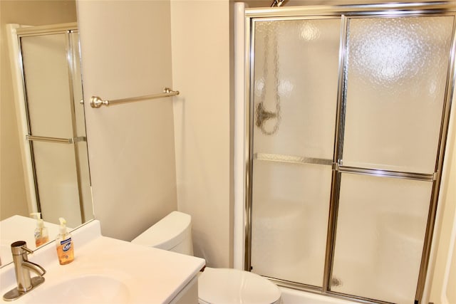 bathroom with toilet, vanity, and a shower with shower door