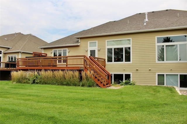 rear view of property with stairs, a deck, a lawn, and roof with shingles