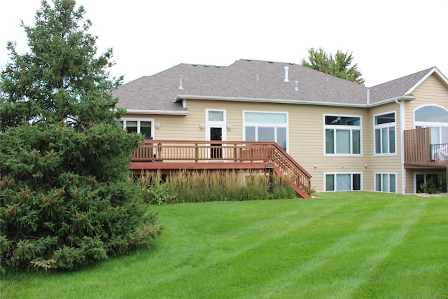 rear view of house with a shingled roof, a yard, and a wooden deck