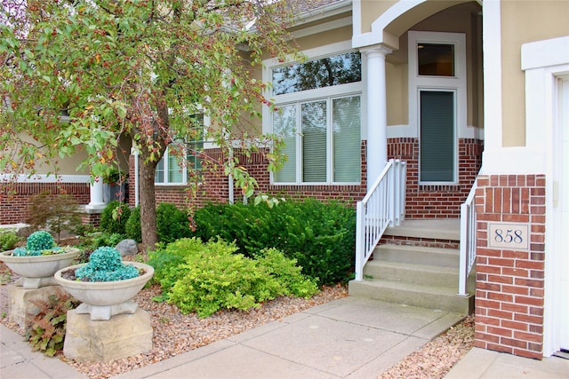 property entrance with stucco siding and brick siding