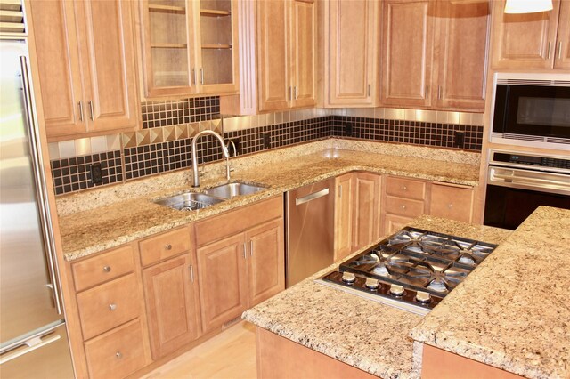 kitchen featuring sink, stainless steel appliances, light stone countertops, and tasteful backsplash