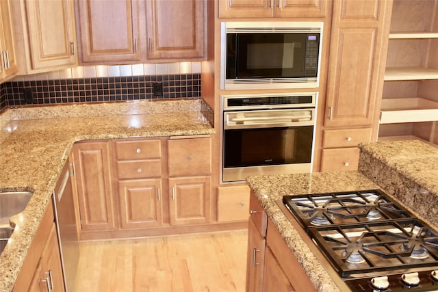 kitchen featuring wood finished floors, appliances with stainless steel finishes, backsplash, light stone countertops, and open shelves