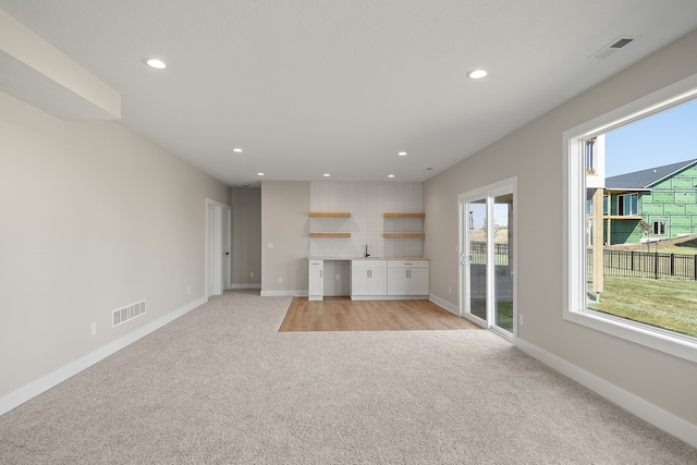 unfurnished living room featuring light carpet