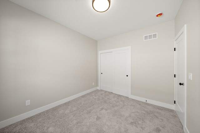 unfurnished bedroom featuring a closet and light colored carpet