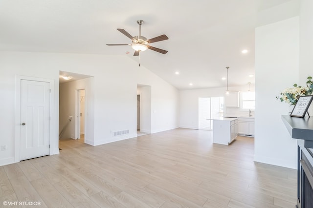 unfurnished living room featuring ceiling fan, vaulted ceiling, and light hardwood / wood-style floors