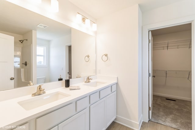 bathroom with tile patterned floors, toilet, walk in shower, and vanity