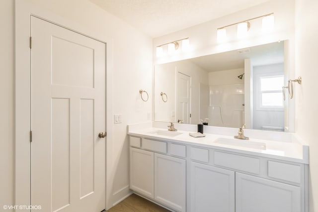 bathroom with a textured ceiling, toilet, a shower, and vanity