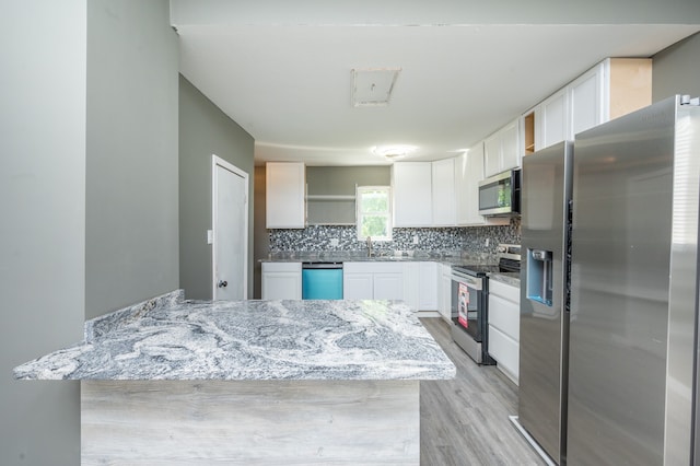 kitchen with tasteful backsplash, white cabinets, stainless steel appliances, light stone countertops, and light wood-type flooring