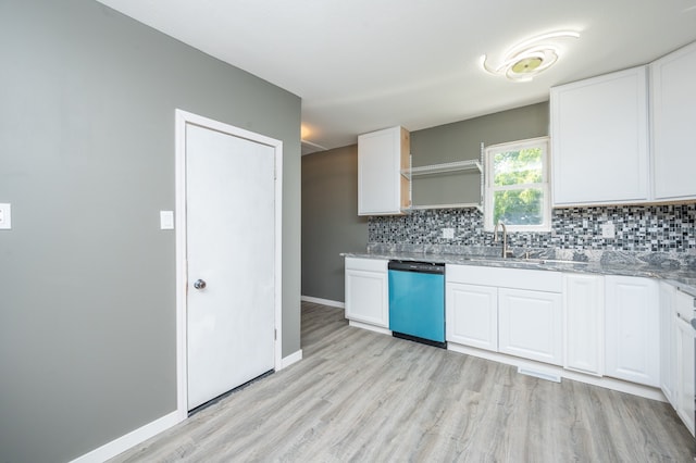 kitchen with white cabinets, backsplash, stainless steel dishwasher, light hardwood / wood-style floors, and light stone counters