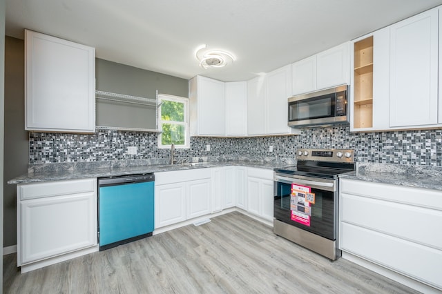 kitchen featuring sink, appliances with stainless steel finishes, backsplash, light hardwood / wood-style floors, and white cabinets