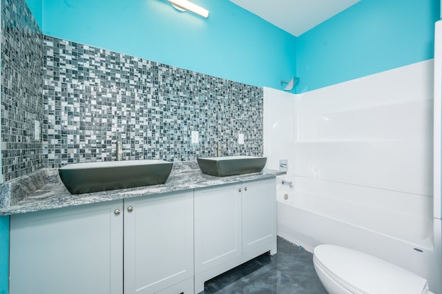 bathroom featuring tasteful backsplash, vanity, toilet, and a bathing tub