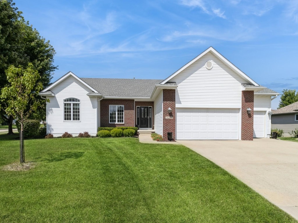 ranch-style house with brick siding, a shingled roof, concrete driveway, an attached garage, and a front yard