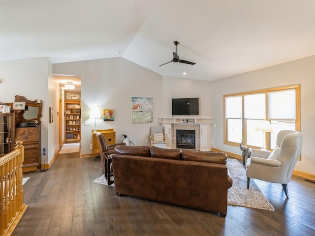 living room featuring a tile fireplace, dark hardwood / wood-style flooring, vaulted ceiling, and ceiling fan