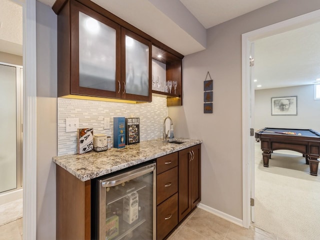 bar featuring sink, light stone countertops, light carpet, decorative backsplash, and beverage cooler