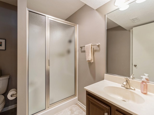 bathroom with vanity, a shower with shower door, and toilet