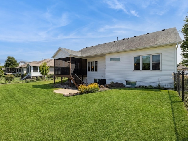 rear view of house featuring a sunroom and a lawn