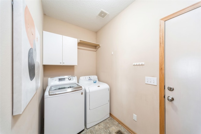 clothes washing area featuring cabinets, washer and dryer, and a textured ceiling