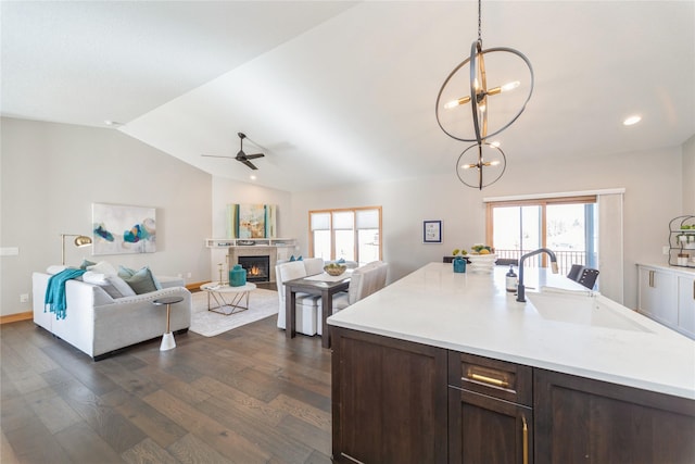 kitchen with lofted ceiling, sink, dark brown cabinets, dark hardwood / wood-style floors, and decorative light fixtures