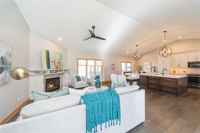 living room featuring lofted ceiling, dark hardwood / wood-style floors, ceiling fan with notable chandelier, and a tile fireplace