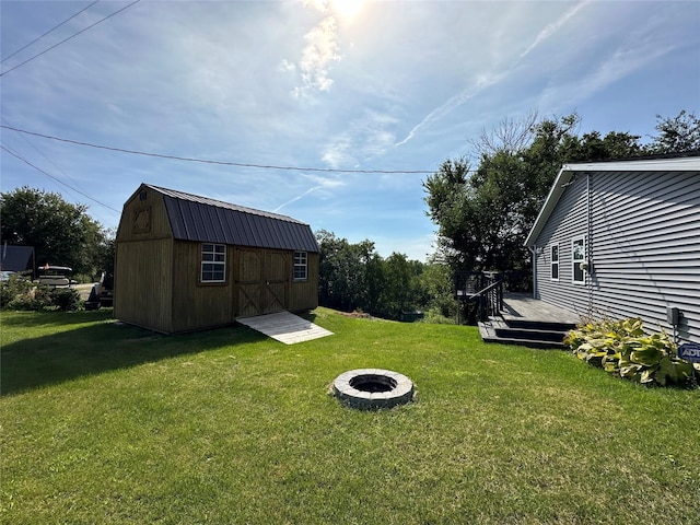 view of yard with a storage unit, a wooden deck, an outdoor fire pit, and an outdoor structure