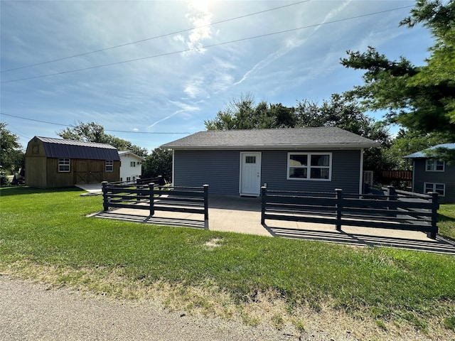 view of front of property featuring a patio, a front yard, an outdoor structure, and fence