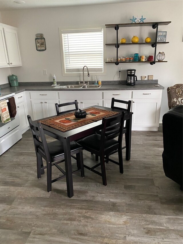 kitchen with a sink, dark countertops, dark wood-type flooring, and white electric stove