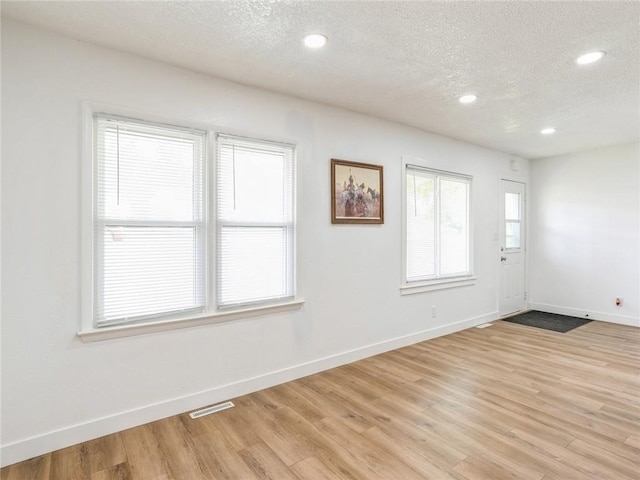 spare room with a textured ceiling and light hardwood / wood-style floors