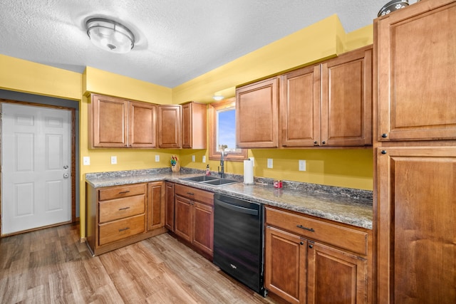 kitchen with black dishwasher, a textured ceiling, sink, light wood-type flooring, and dark stone countertops