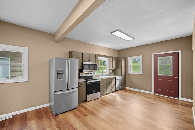 kitchen featuring light hardwood / wood-style floors, stainless steel appliances, a textured ceiling, beam ceiling, and sink