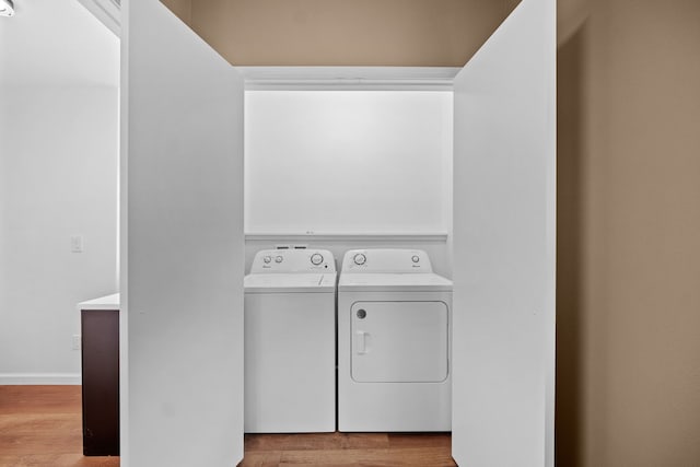 clothes washing area featuring light hardwood / wood-style floors and washing machine and dryer