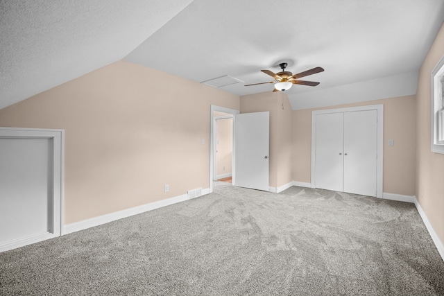 unfurnished bedroom featuring ceiling fan, carpet floors, vaulted ceiling, and a textured ceiling