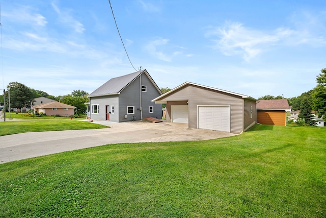 view of front of house featuring a garage, a front lawn, and an outbuilding