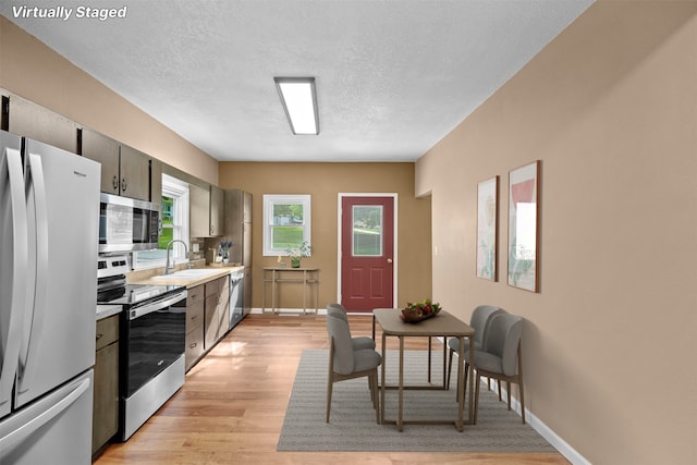 kitchen featuring a textured ceiling, stainless steel appliances, sink, and light hardwood / wood-style floors