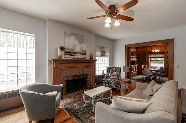 living room featuring radiator heating unit, ceiling fan, hardwood / wood-style floors, and a fireplace