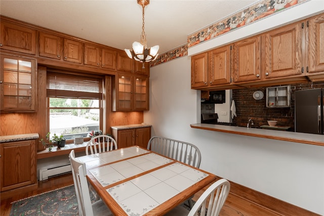 dining area with hardwood / wood-style flooring, sink, baseboard heating, and a chandelier