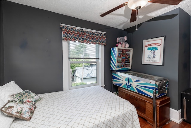 bedroom featuring ceiling fan, hardwood / wood-style floors, a textured ceiling, and lofted ceiling